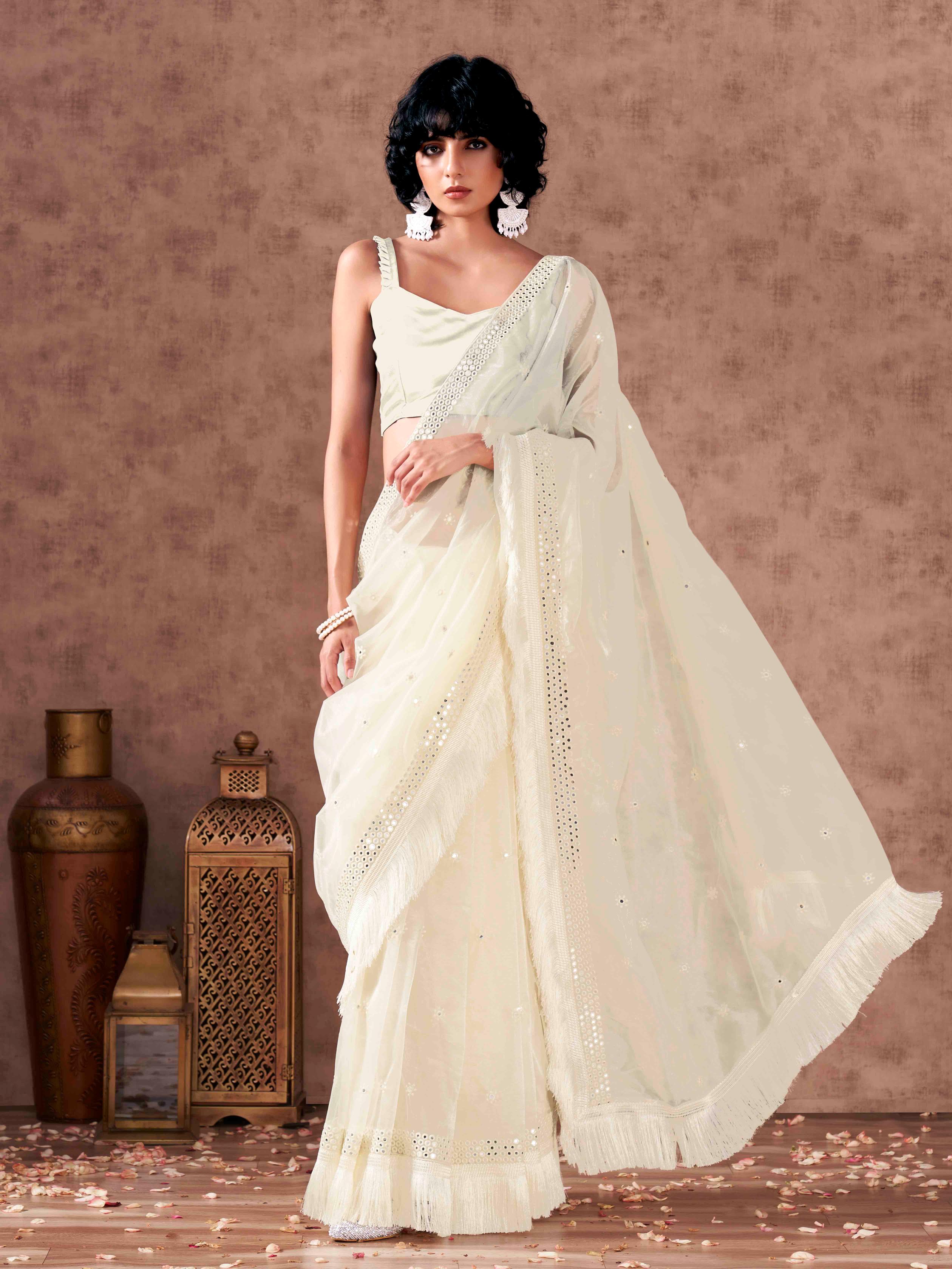 Off white colored supernet saree with faux mirror embroidery and tassles lace