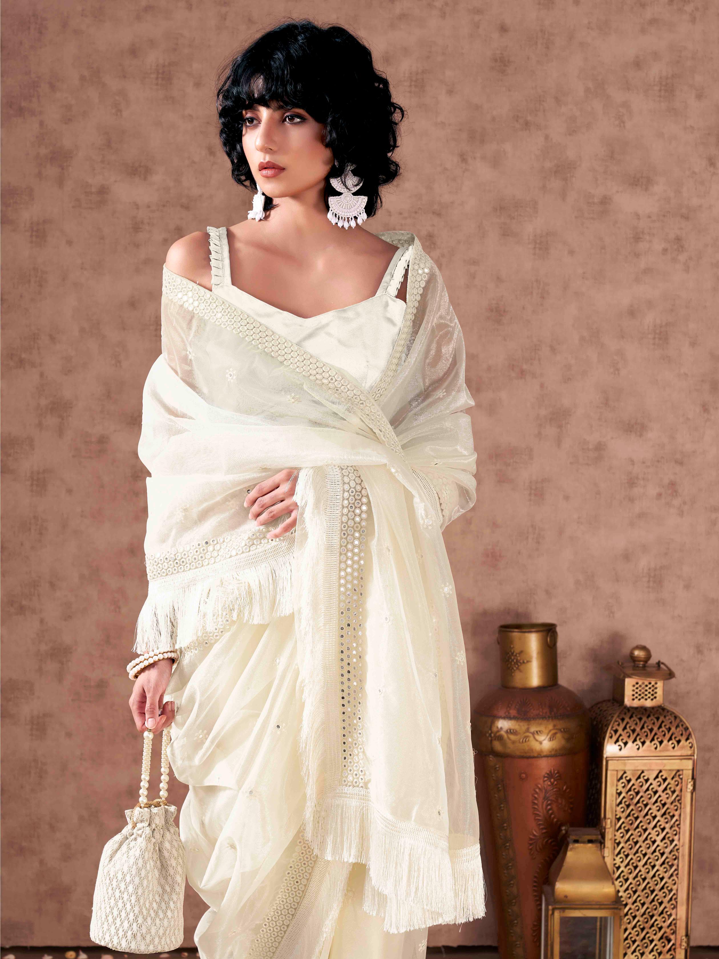 Off white colored supernet saree with faux mirror embroidery and tassles lace