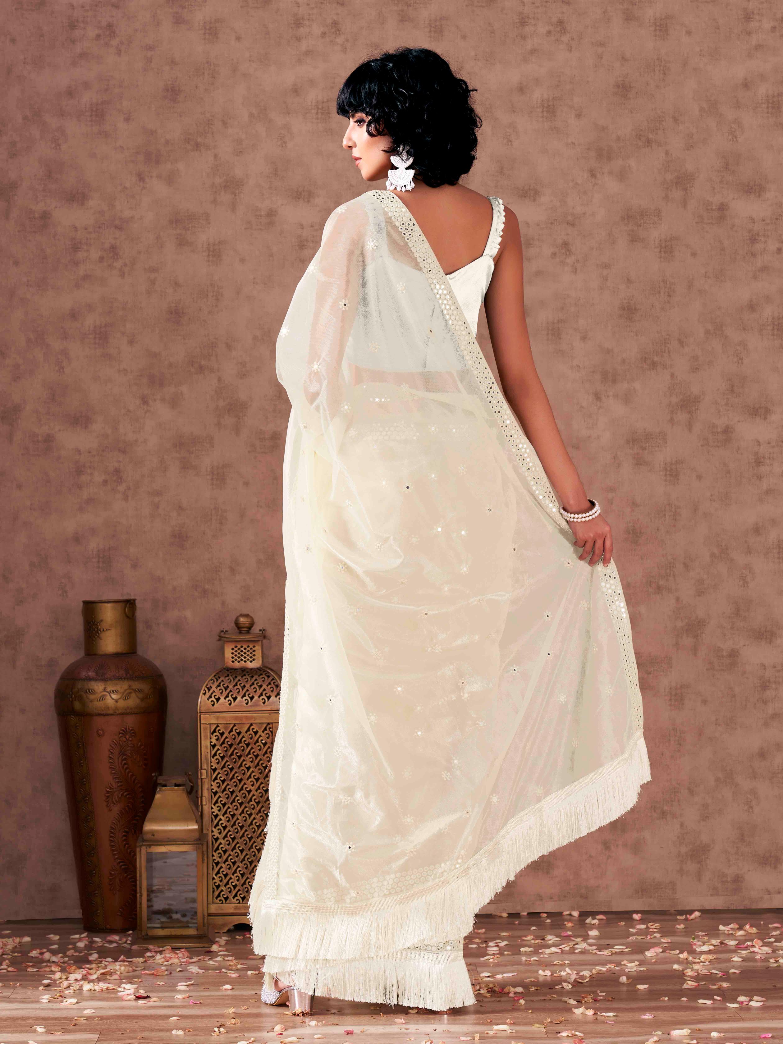 Off white colored supernet saree with faux mirror embroidery and tassles lace