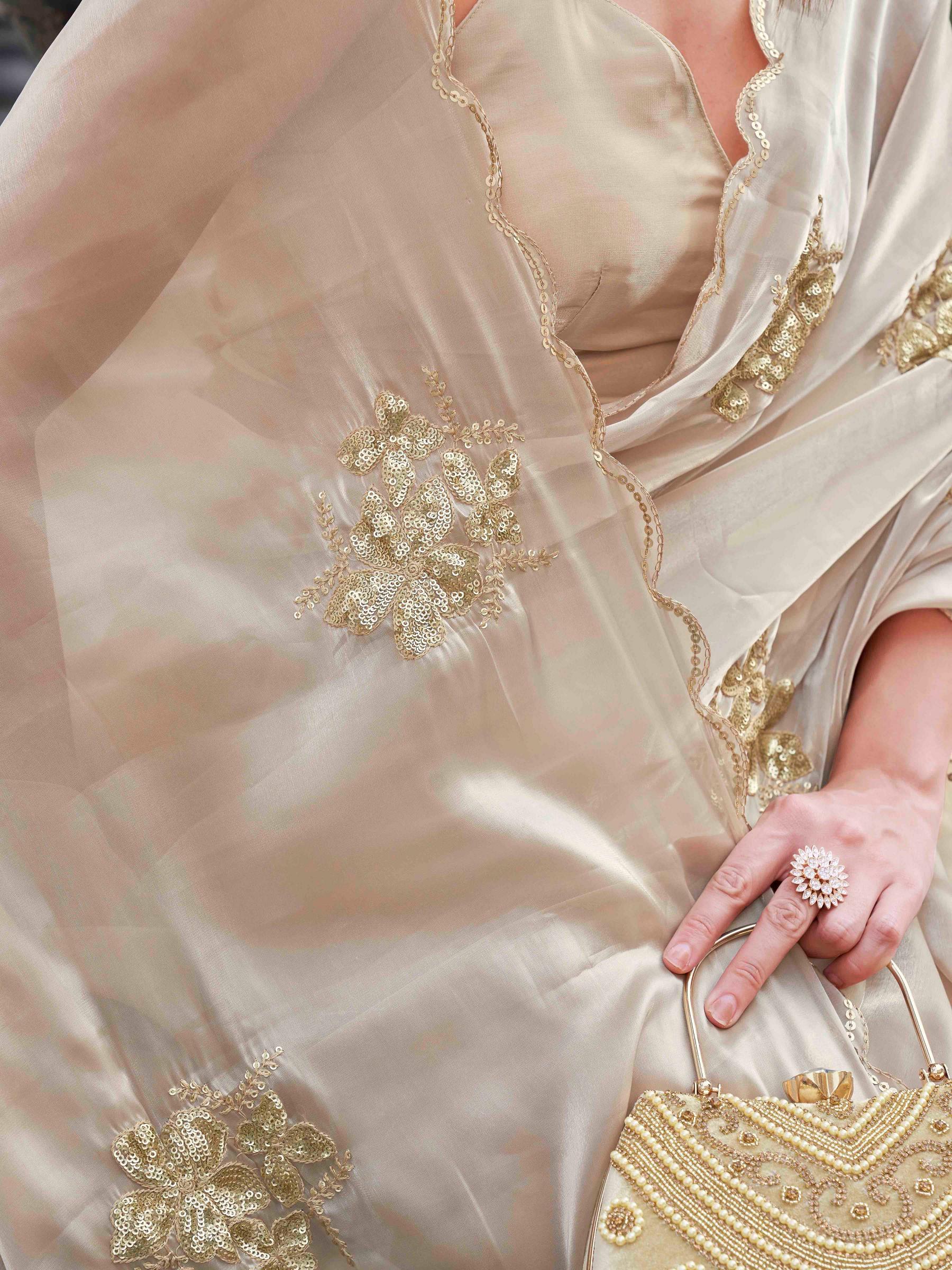 Beige colored burbery satin saree with sequinned embroidered butta on pallu and scalloped border