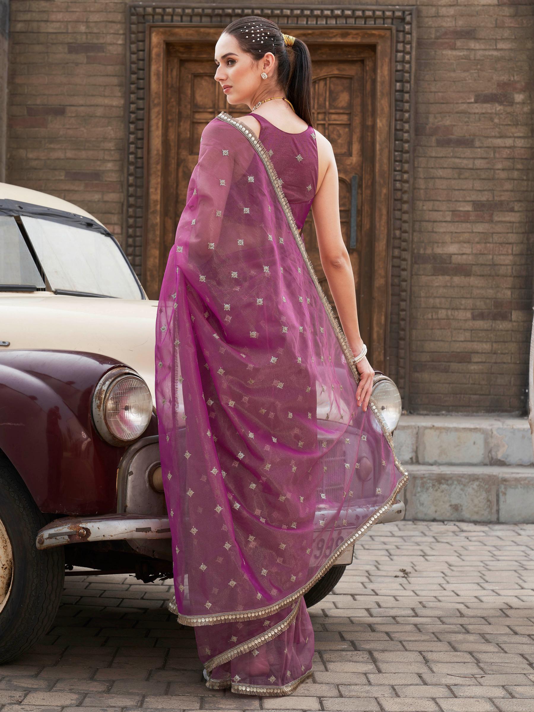 Pink colored shimmer net saree with sequinned butti and embroidered border
