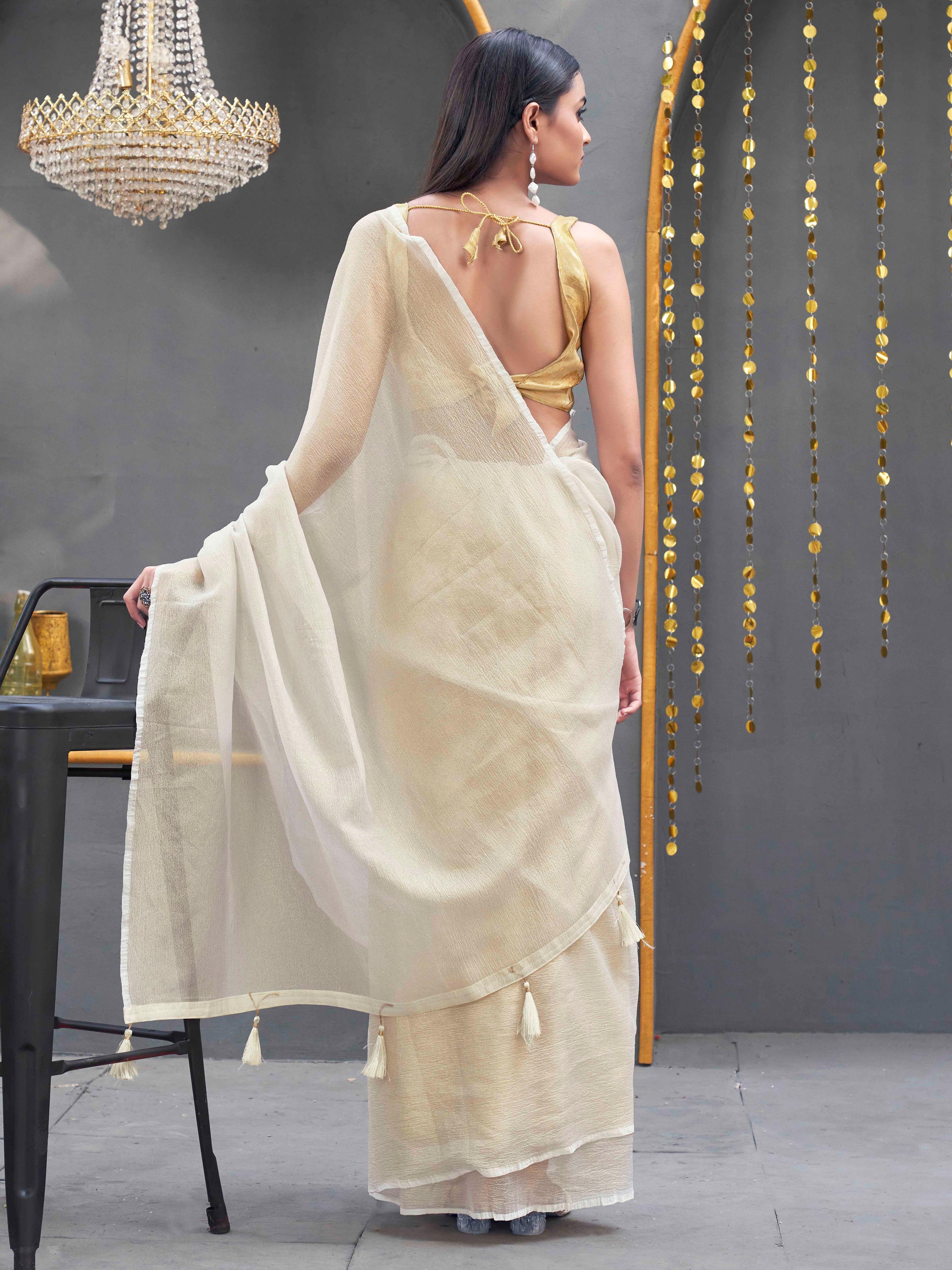 Cream colored designer crunchy saree with tassles on pallu and foil embellishment