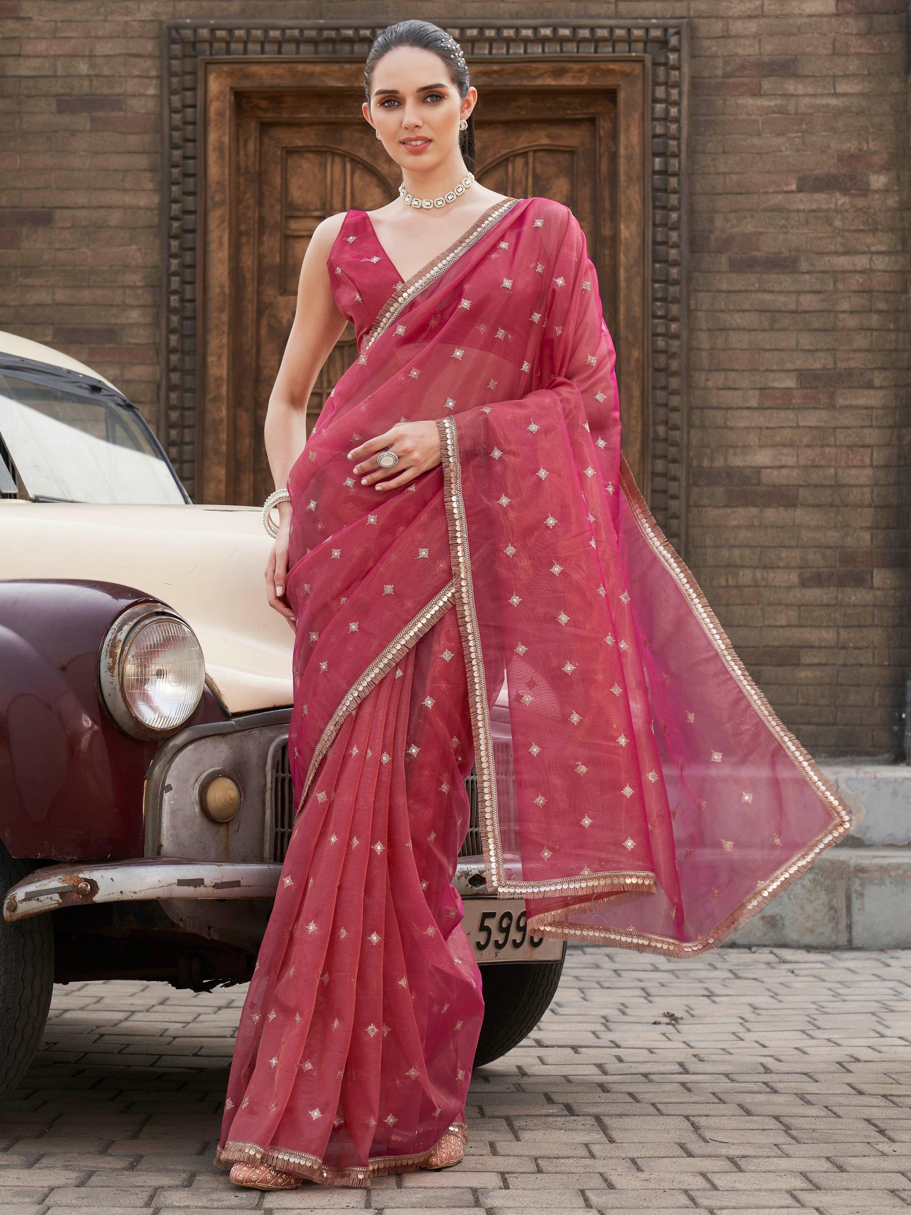 Pink colored shimmer net saree with sequinned butti and embroidered border