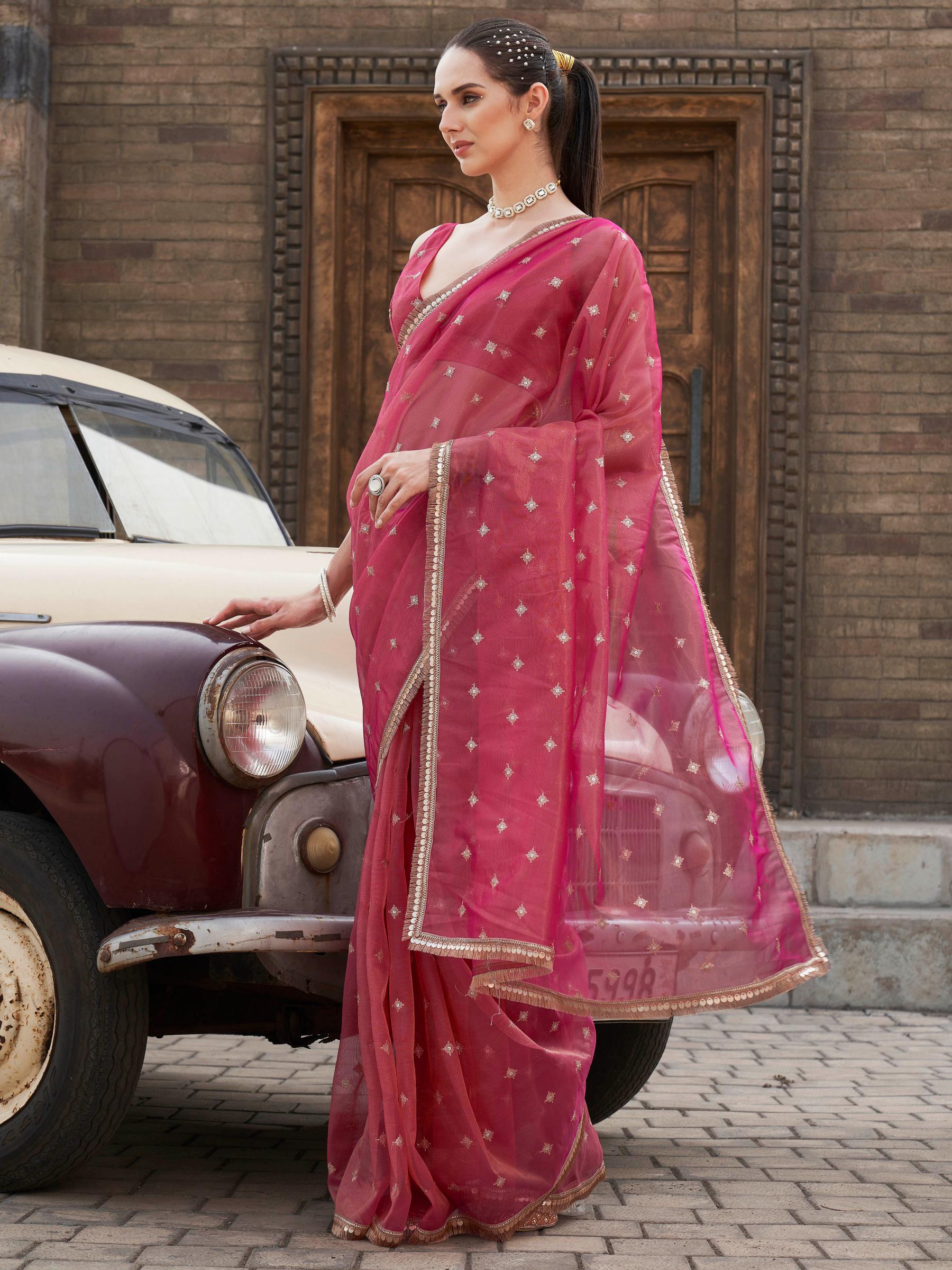 Pink colored shimmer net saree with sequinned butti and embroidered border