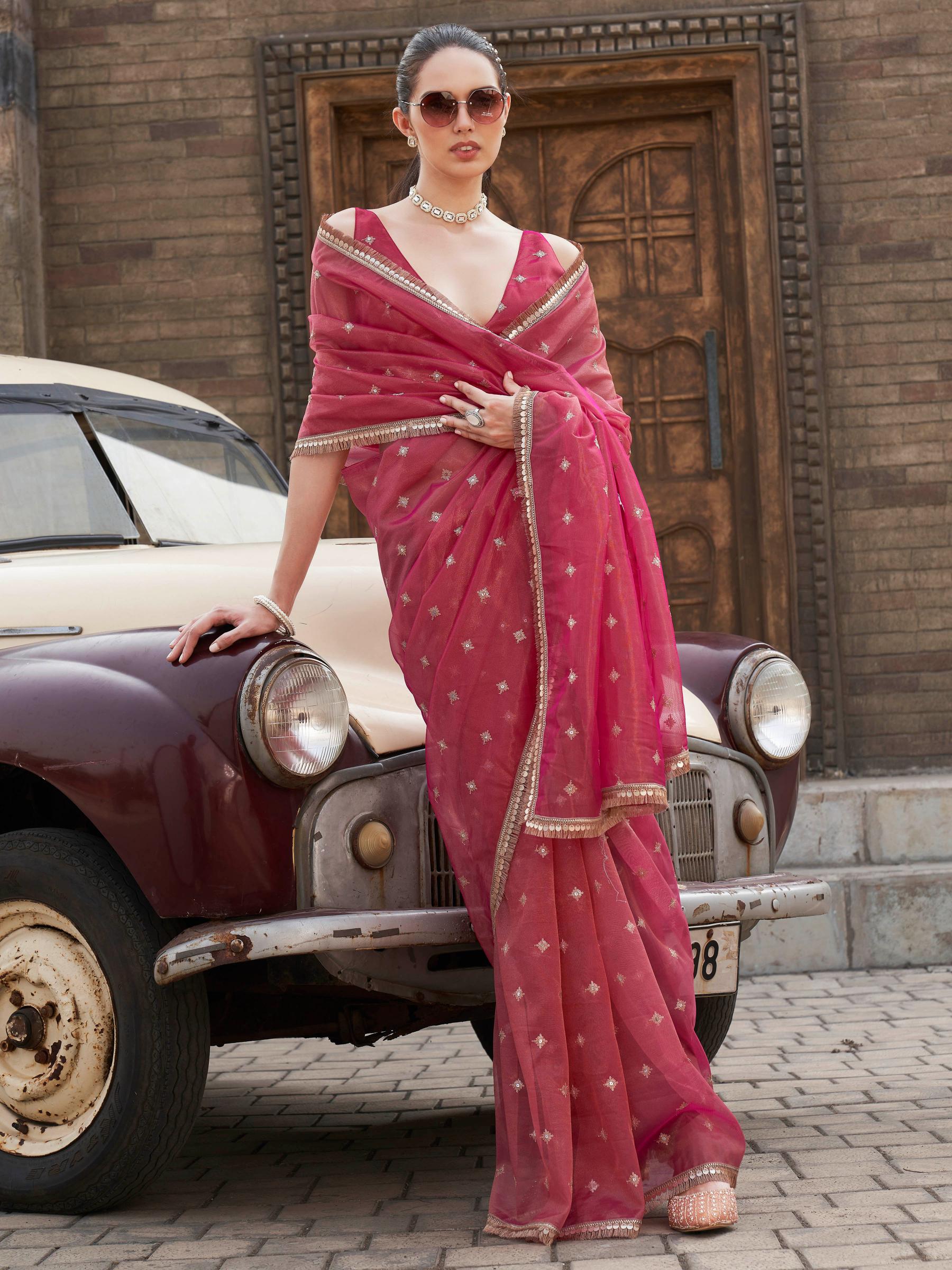 Pink colored shimmer net saree with sequinned butti and embroidered border