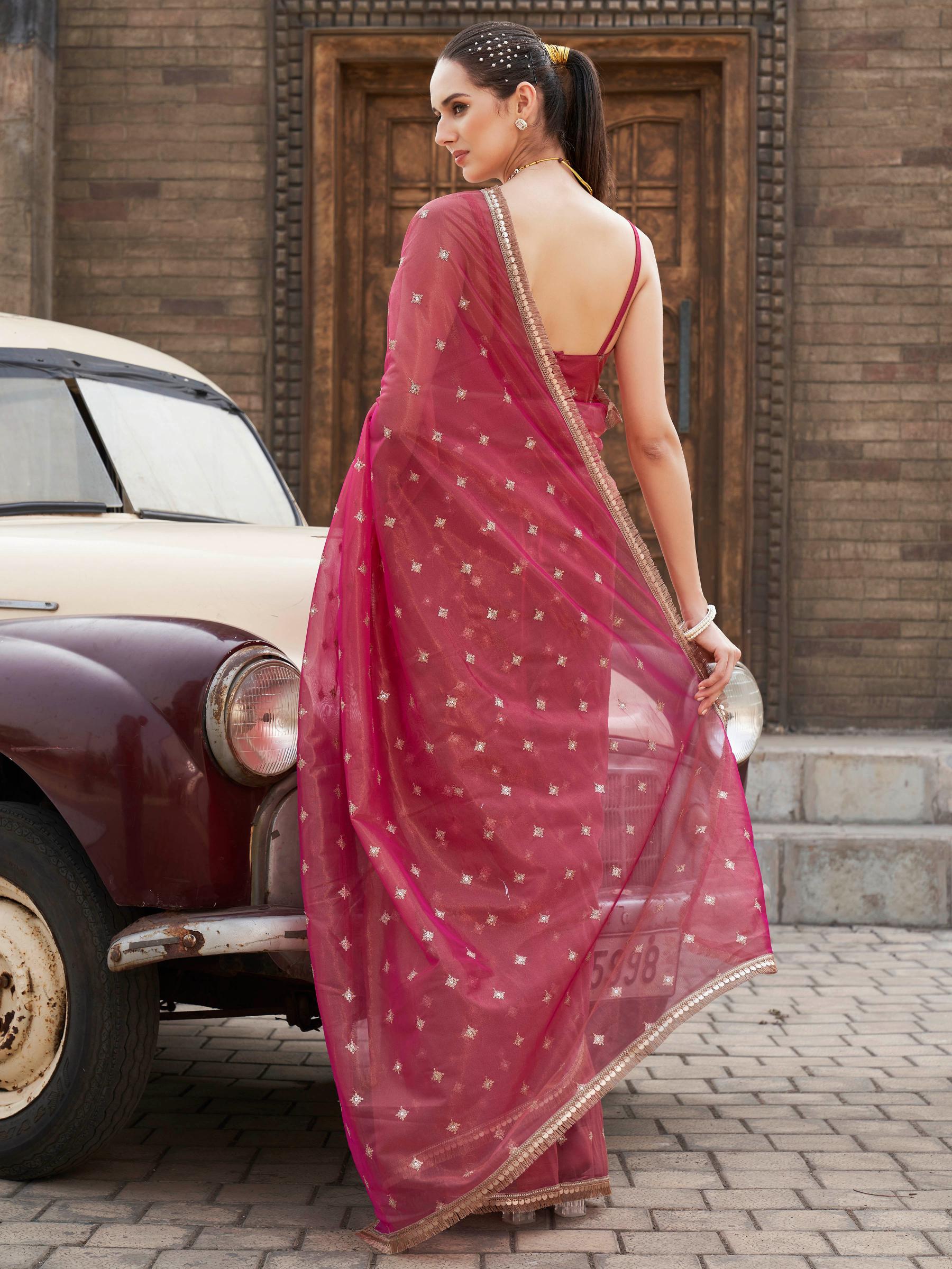Pink colored shimmer net saree with sequinned butti and embroidered border