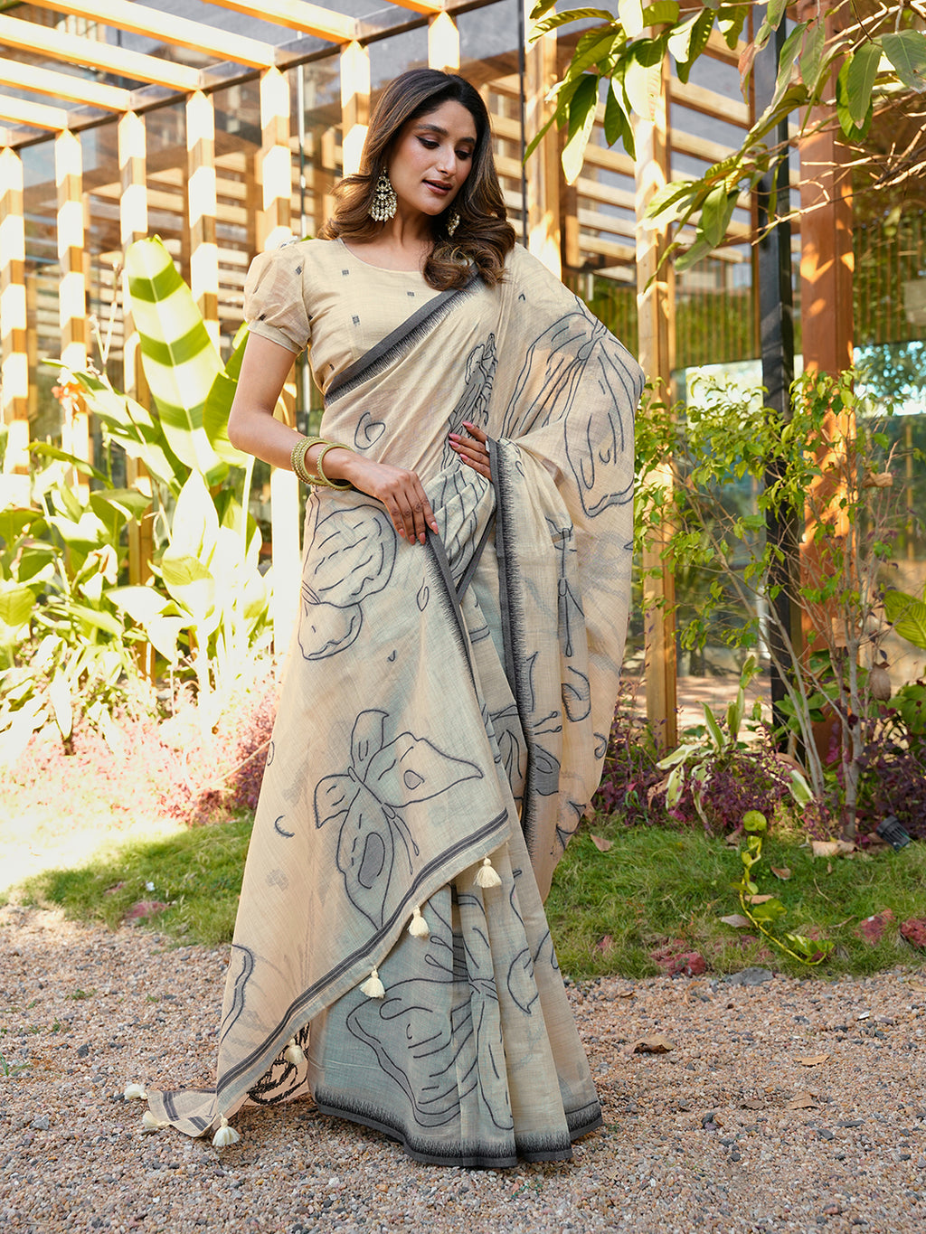 Beige colored muga cotton saree with tassles on pallu