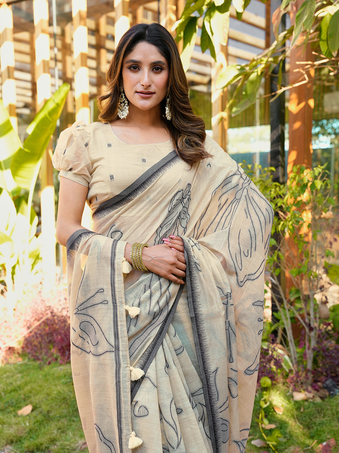 Beige colored muga cotton saree with tassles on pallu