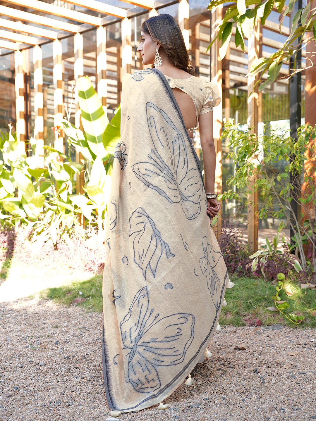 Beige colored muga cotton saree with tassles on pallu