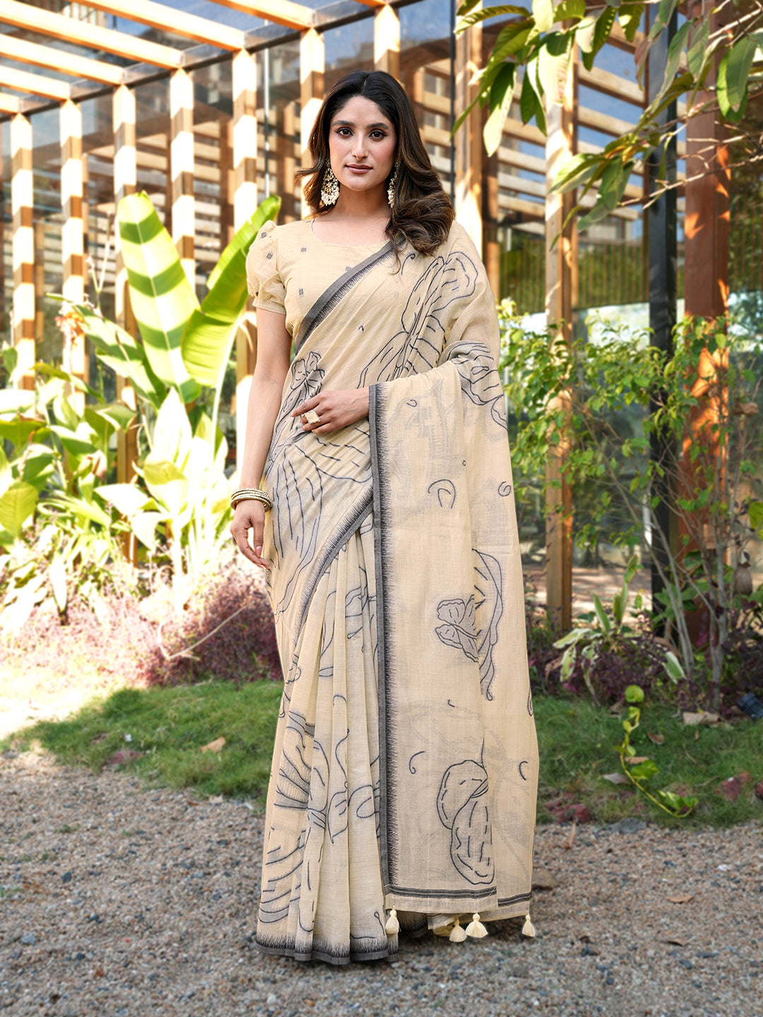Beige colored muga cotton saree with tassles on pallu